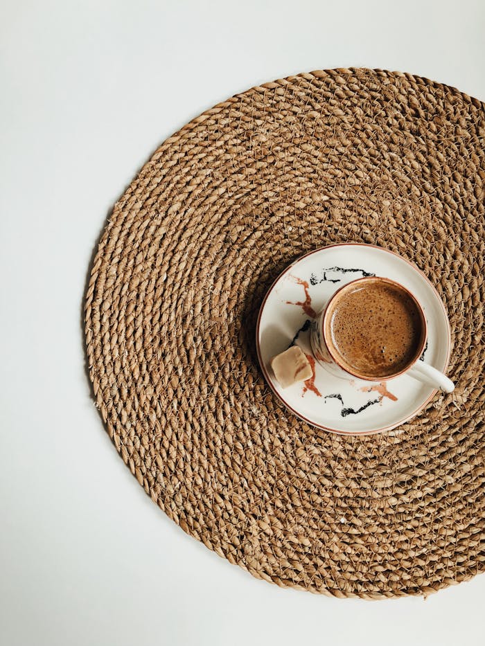 A beautifully crafted cup of Turkish coffee sits on a jute mat, highlighting traditional design.